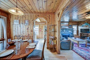 A wooden interior with a dining area, a fireplace, and a television.