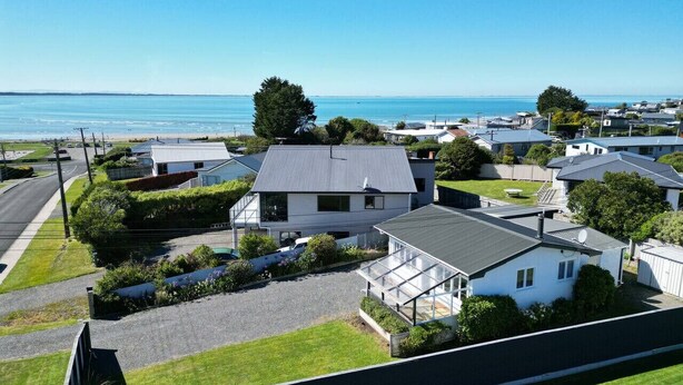 Een woonwijk met huizen, een oprit en uitzicht op zee.