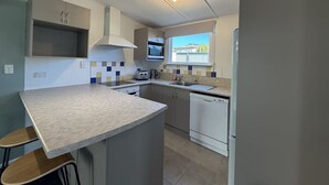 Een compacte keuken met een centraal kookeiland, geïntegreerde apparatuur en een raam dat voor natuurlijk licht zorgt.