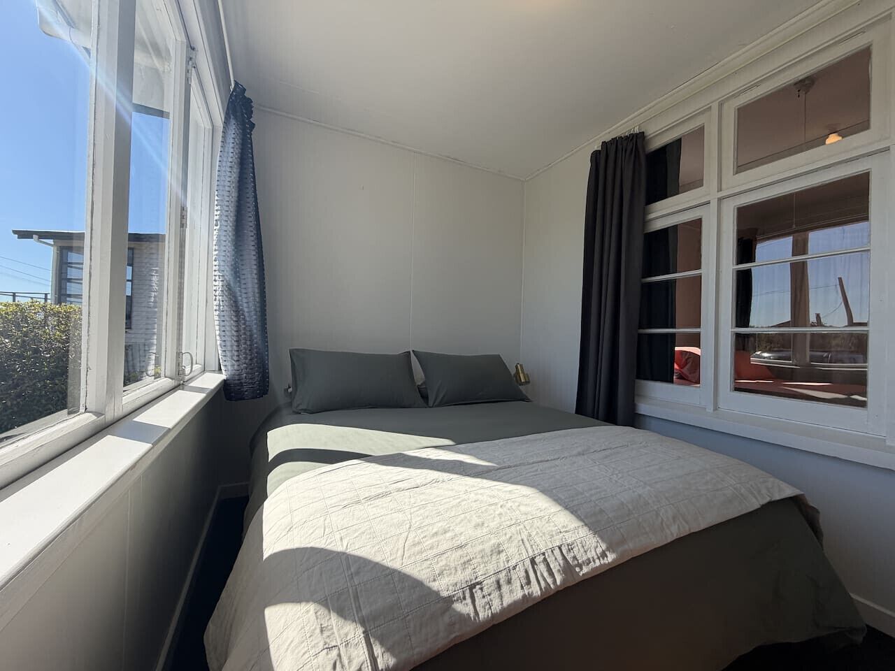 Een slaapkamer met een bed, een raam en gordijnen.