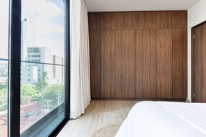 Ein Schlafzimmer mit großem Fenster, Holzschrank und Bett.