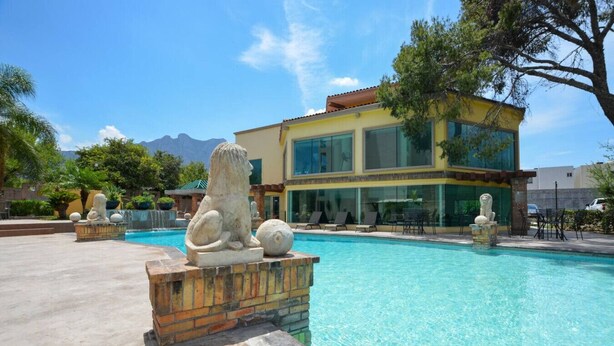 A pool with stone sculptures, a modern building with large windows, and a mountain in the background. - ¡Luxury in Santa Catarina! King bed + Wifi | 5 ppl (Santa Catarina)