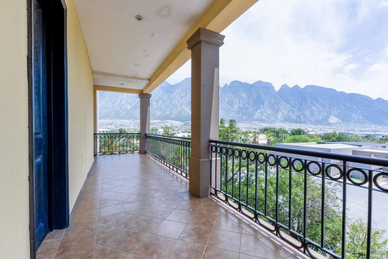 A balcony with a view of mountains and a cityscape.