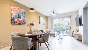 A dining area with a round table, grey upholstered chairs, a vase with flowers, and a ceiling fan. - ¡Luxury in Santa Catarina! King bed + Wifi | 5 ppl (Santa Catarina)