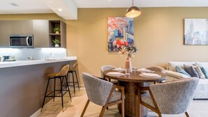 A modern kitchen with a microwave, bar stools, and a dining table set for four. - ¡Luxury in Santa Catarina! King bed + Wifi | 5 ppl (Santa Catarina)