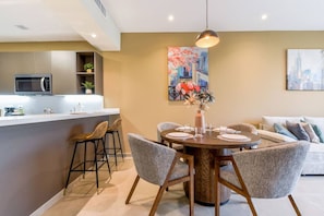 Uma cozinha moderna com micro-ondas, banquetas de bar e uma mesa de jantar para quatro pessoas.