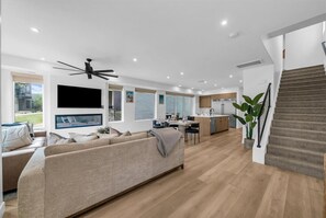 Ein modernes Wohnzimmer mit einer Couch, einem Flachbildfernseher und einem Deckenventilator.