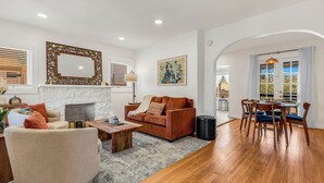 A living room with a fireplace, a sofa, a dining table with chairs, and a large mirror.