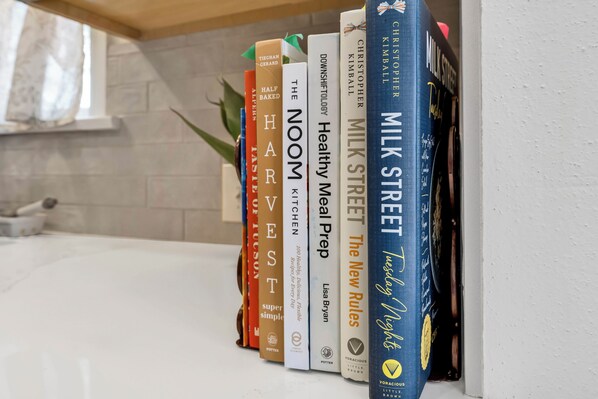 A bookshelf with books titled 'The Nook,' 'Half Baked,' 'The New Rules,' 'Milk Street,' and 'Tuesday Nights.' - Charming Winter Getaway in Blenman-Elm near U of A (Tucson)