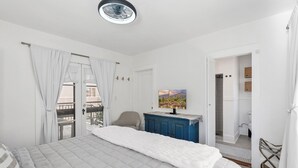 A bedroom with a bed, a blue cabinet, a painting, and a door leading to a bathroom.