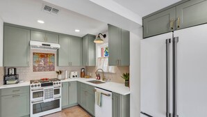 A modern kitchen with a built-in oven, a stainless steel refrigerator, and light green cabinets.