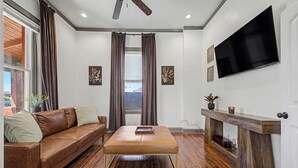 Un salon avec un canapé en cuir marron, une table basse en bois, une cheminée et un téléviseur à écran plat fixé au mur.