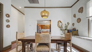 Un coin repas avec une table en bois, des chaises, un tapis à motifs et un luminaire suspendu.