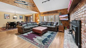Una sala de estar acogedora con un sofá modular, una chimenea y un comedor con mesa y sillas.