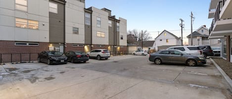 Un parking rempli de voitures, des bâtiments adjacents dotés de grandes fenêtres et un ciel dégagé.