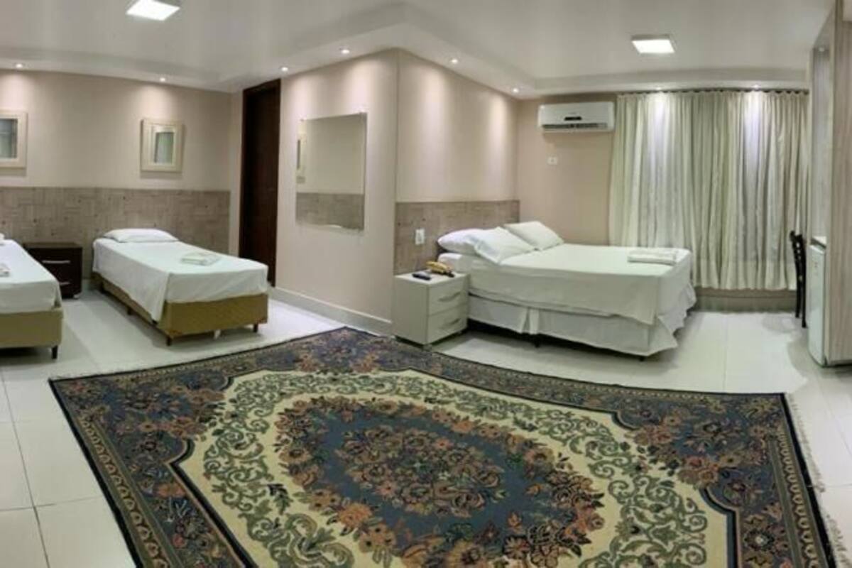 Habitación de hotel con dos camas, un tapete decorativo grande, un televisor y un baño con ducha.