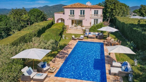 Una casa de dos pisos con piscina, mobiliario exterior y vistas del paisaje circundante.