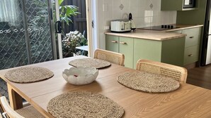 Un espace repas avec une table en bois, des sets de table en fibres tressées et des chaises en métal.