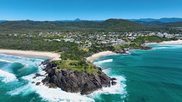 Une ville côtière dotée d’un promontoire rocheux, d’une plage et d’un quartier résidentiel.