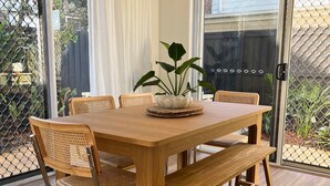 Une table à manger en bois, des chaises, un luminaire suspendu et une plante en pot.