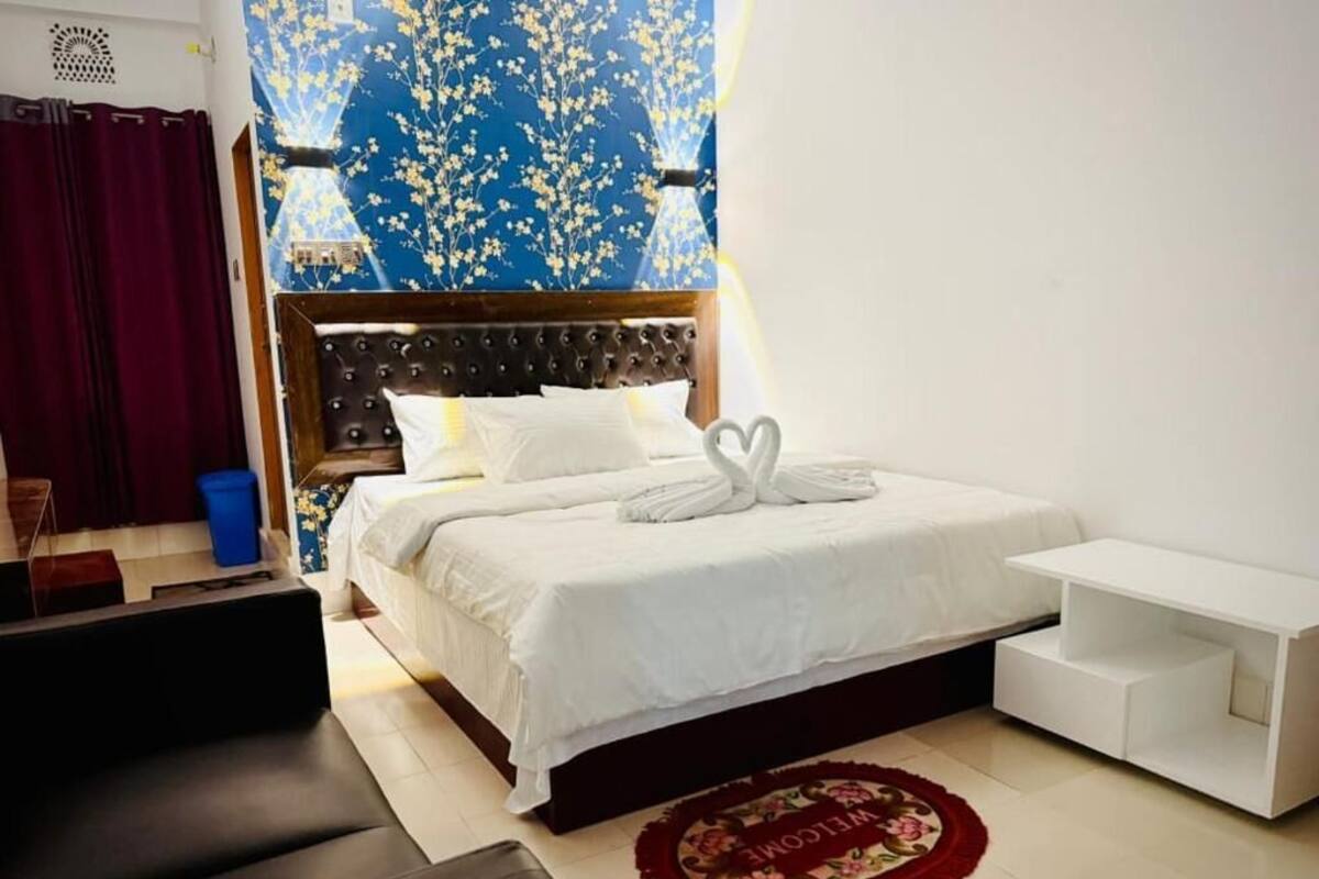 Een hotelkamer met een bed, nachtkastje, bank en decoratieve wand.