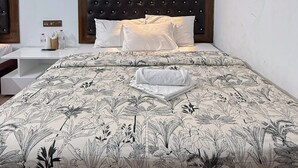 A hotel room with a bed, bedside tables, a wall-mounted air conditioner, and a wall-mounted light fixture. - Hotel Green Land Bandarban (Bandarban)