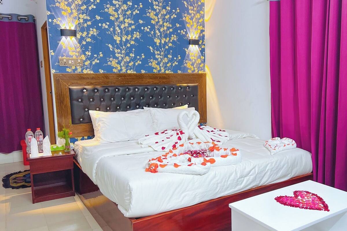 Een hotelkamer met een bed, nachtkastje en decoratieve wand.
