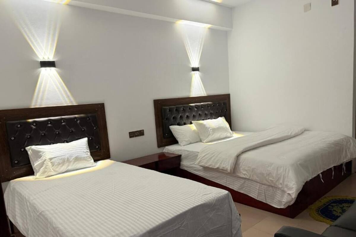 Een hotelkamer met twee bedden, elk voorzien van een hoofdeinde en witte beddengoed.