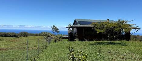 Ein Haus mit einer Solaranlage auf dem Dach, umgeben von einer Wiese und einem Zaun.