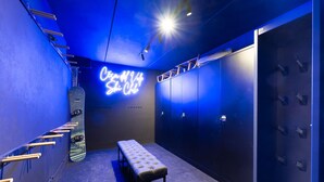 Spogliatoio con insegna al neon, panche e armadietti.