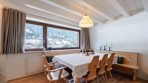Zona pranzo con tavolo, sedie, una panca, una finestra con vista e un lampadario.