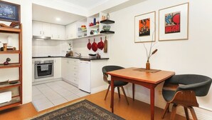 Une cuisine de taille réduite avec des meubles blancs, une table à manger avec des chaises et un tapis sur le sol.