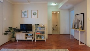 A living room with a TV, bookshelf, and potted plants. - Chippendale Charmer in Ideal Location (Chippendale)
