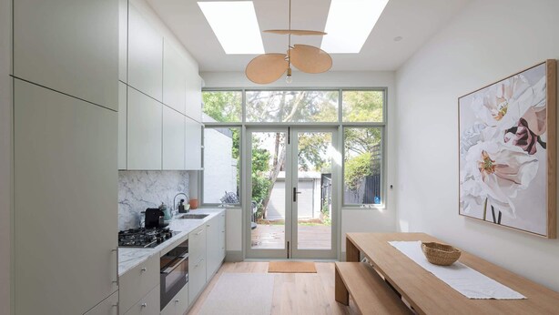 Una cocina moderna con un ventanal grande, una zona de comedor con banco y un ventilador de techo.