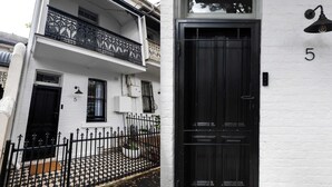 Un edificio de dos plantas con una puerta negra y el número 5 en la pared.