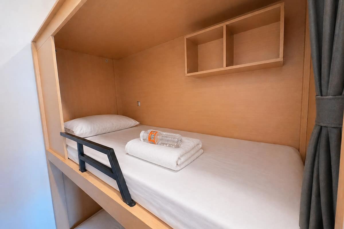 Una cama litera con cabecera, un pequeño estante encima de la cama y una toalla sobre ella.