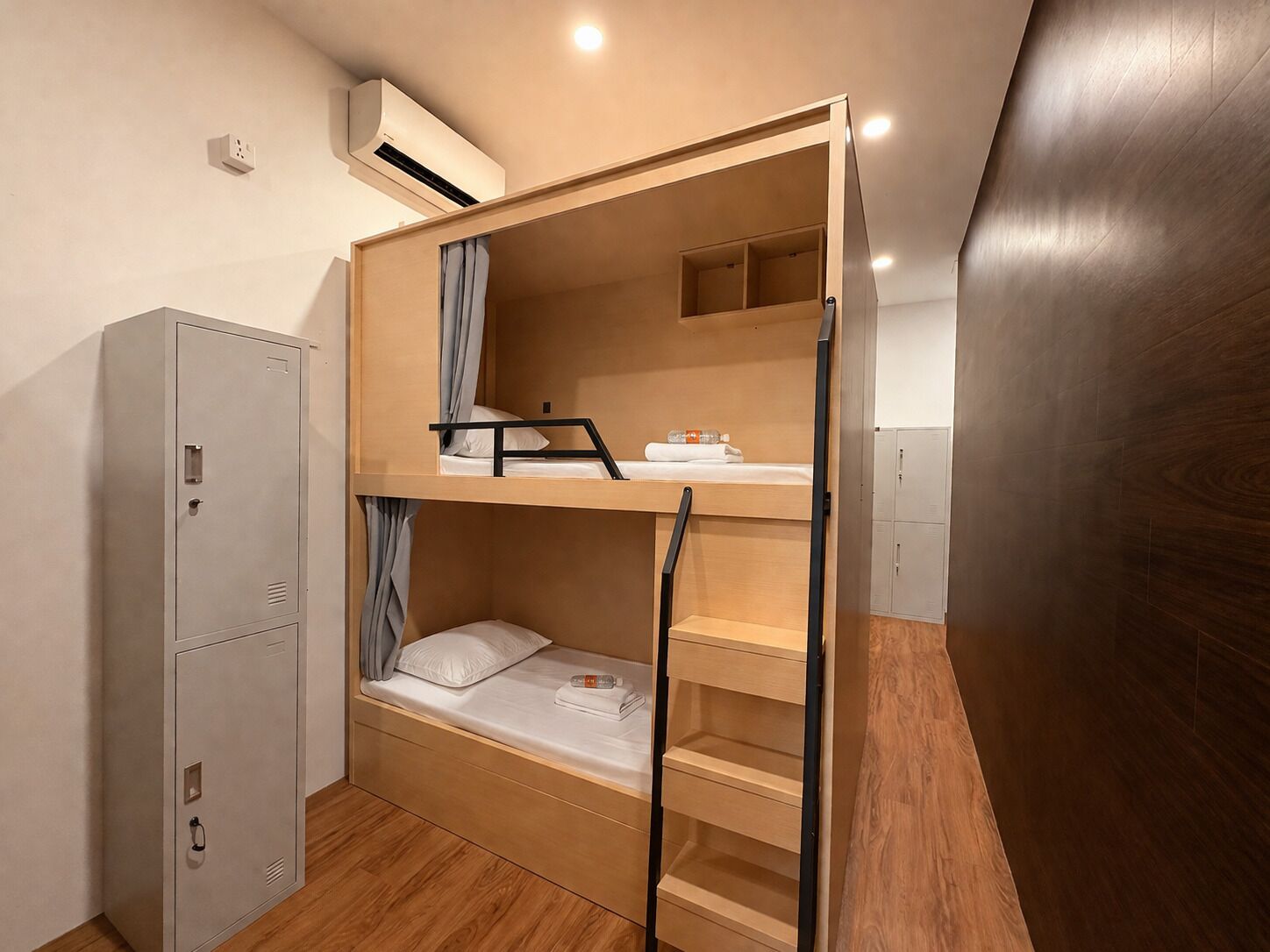 A bunk bed room with a desk, a wardrobe, and a small shelf.