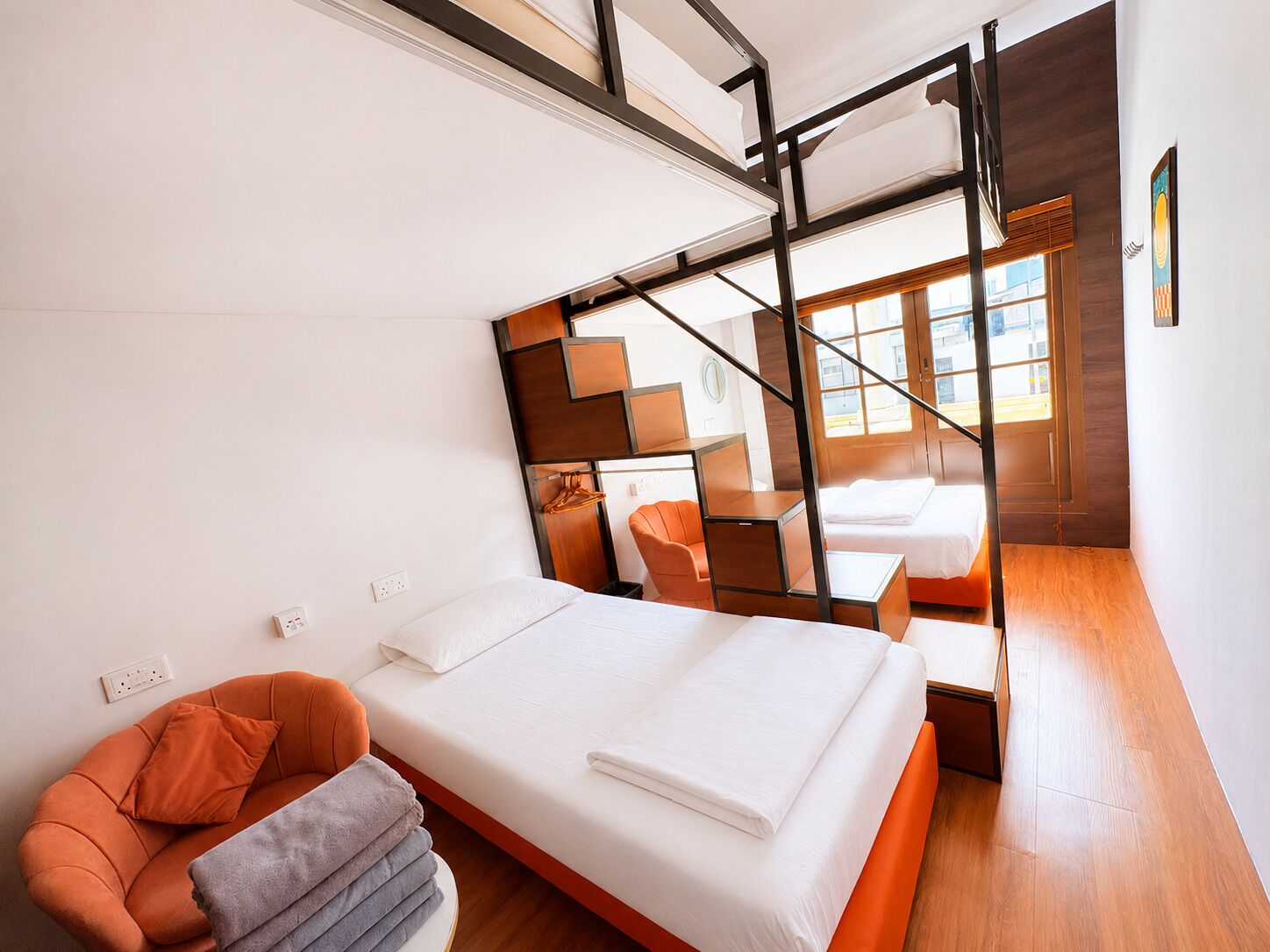A modern hotel room with a bed, a chair, a desk, and a staircase.