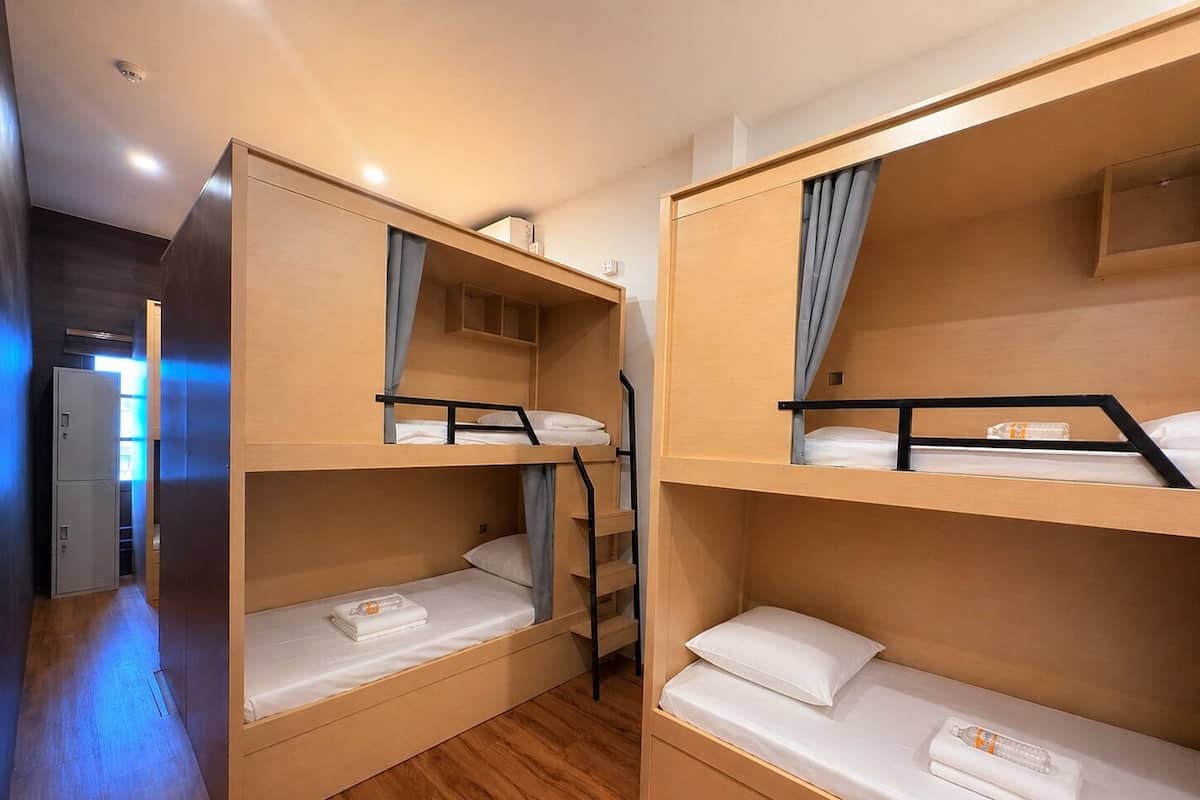 Una habitación con literas, suelo de madera y una puerta que da a otra zona.