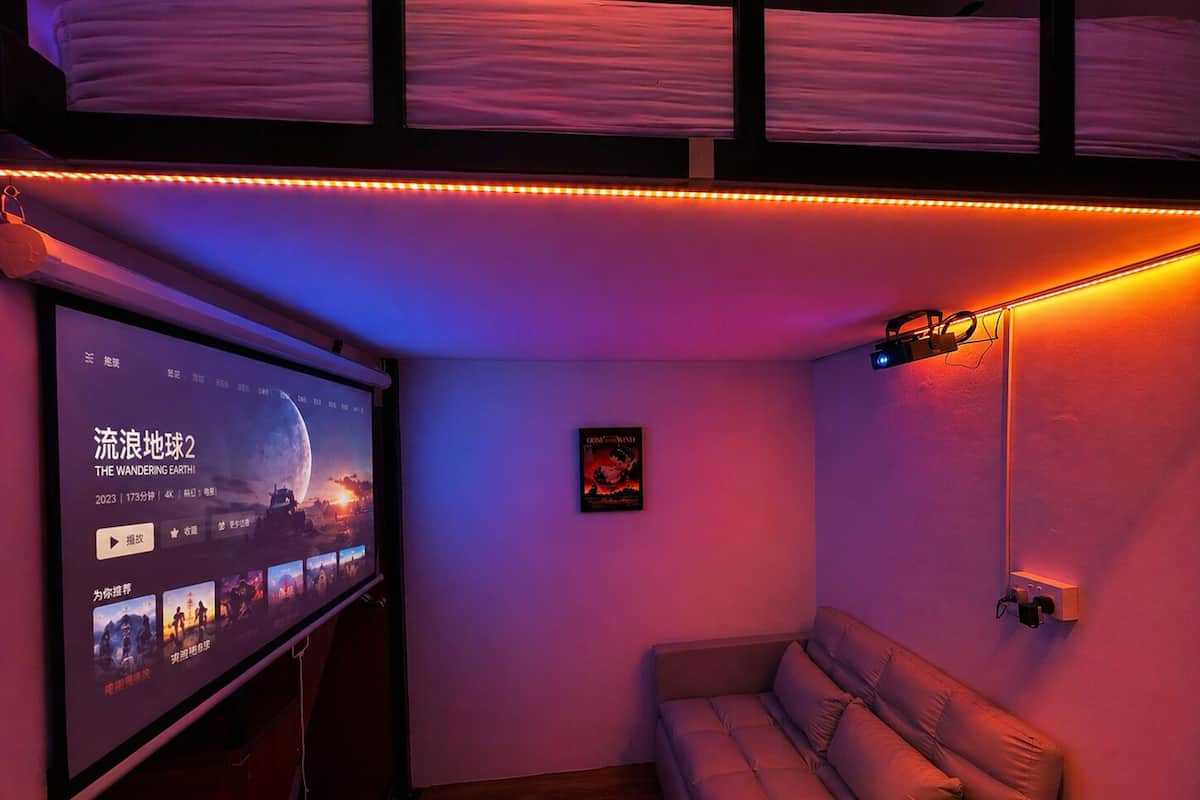 Una habitación acogedora con una pantalla grande, un sofá y una cama litera.