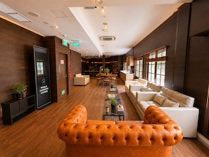 A modern hotel lobby with a mobile charging station, a dining area, and a seating area with sofas and a coffee table. - Bugis Social- Newly Renovated (Singapore)