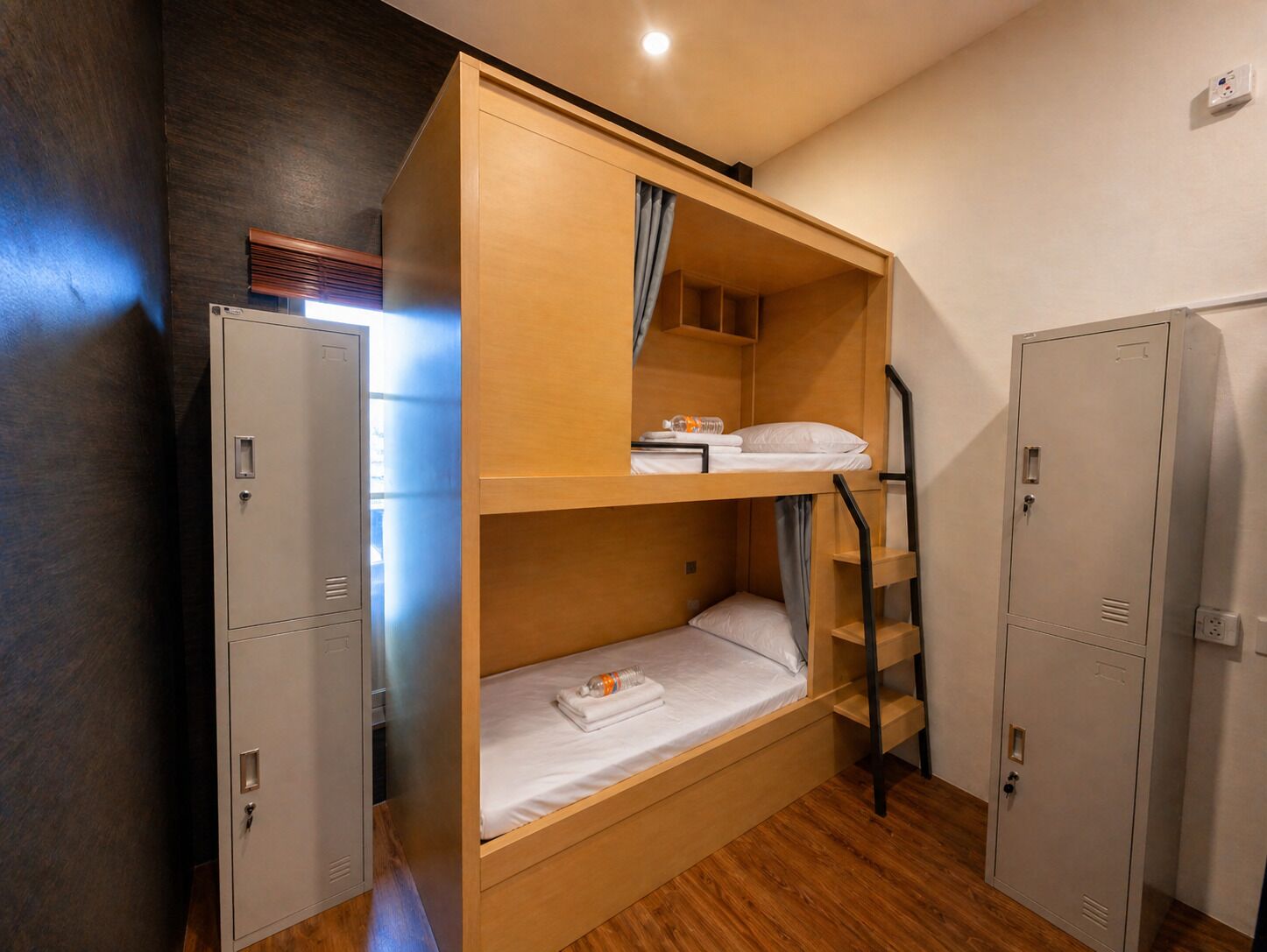 A bunk bed room with a ladder, two metal lockers, and a small shelf.