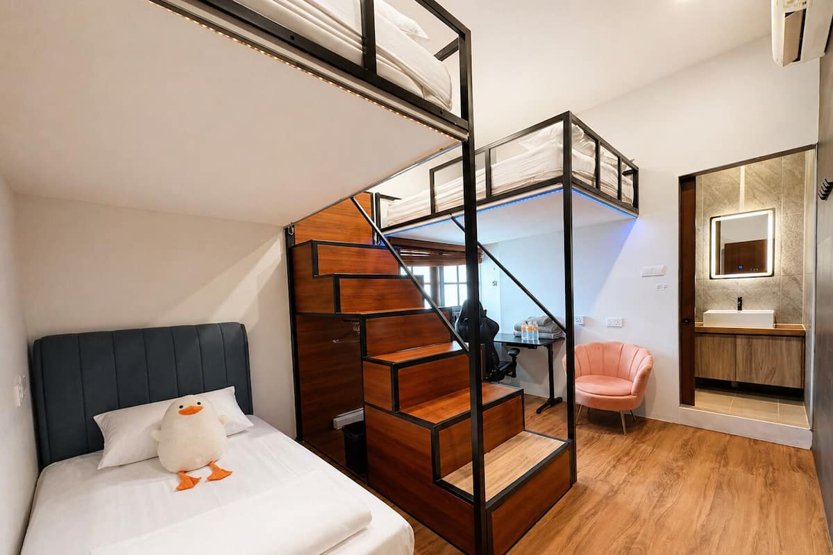 Un dormitorio con cama, escritorio, silla, escalera y baño.