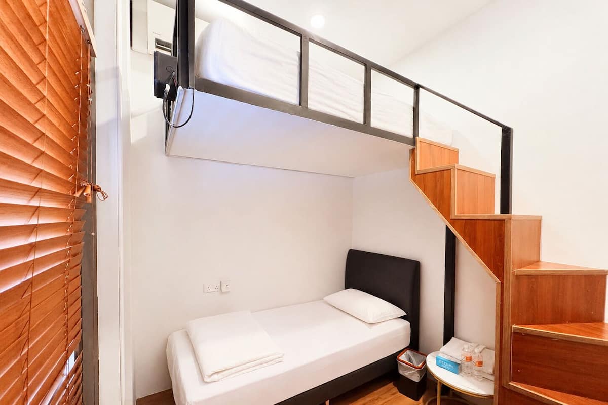 Un dormitorio pequeño con una cama, una mesita y una escalera de madera.