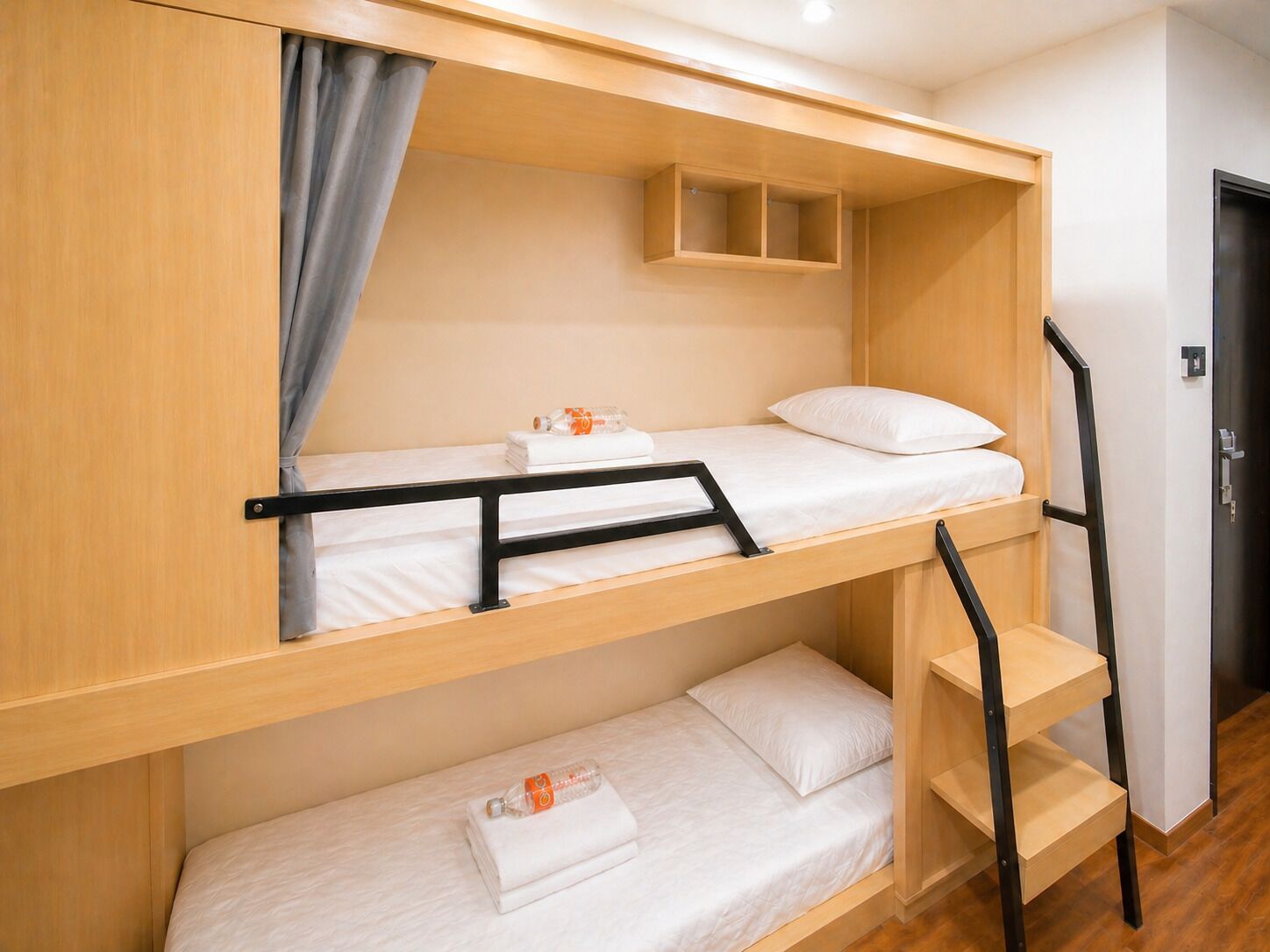 Una camera con un letto a castello, una testiera in legno, un piccolo ripiano e una porta.