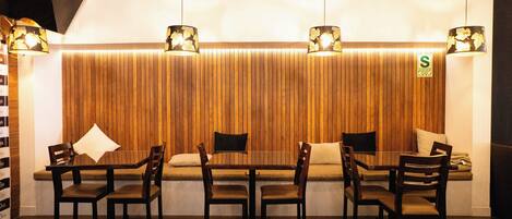 A restaurant with a wooden wall, a long table, and chairs.