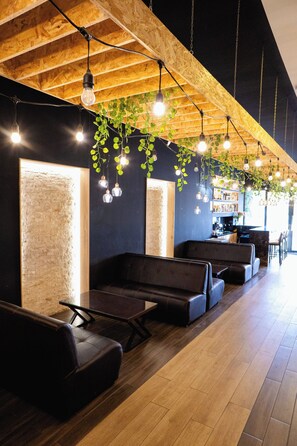 A modern interior with wooden ceiling beams, hanging light bulbs, and green plants. - PRANA (El Tambo)