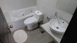 Kylpyhuone, jossa on kylpyamme, wc, pesuallas ja roskakori.
