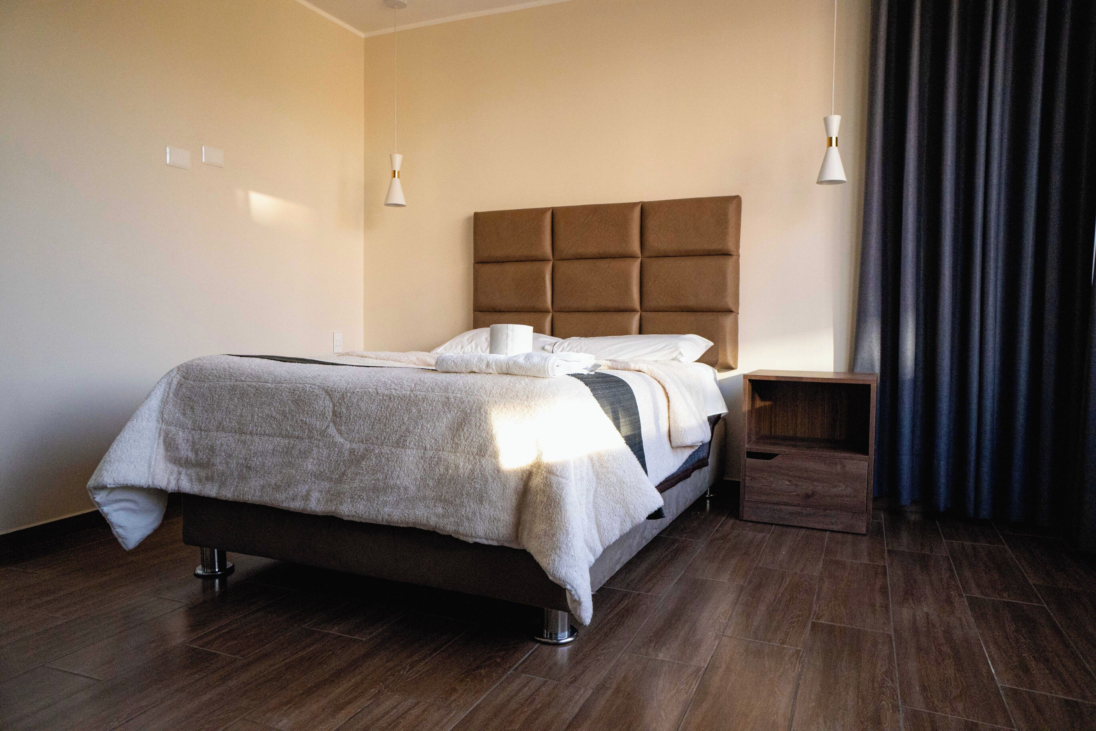 A modern bedroom with a large bed, bedside tables, and a headboard.