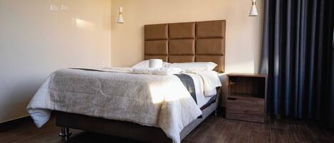 A modern bedroom with a large bed, bedside tables, and a headboard.